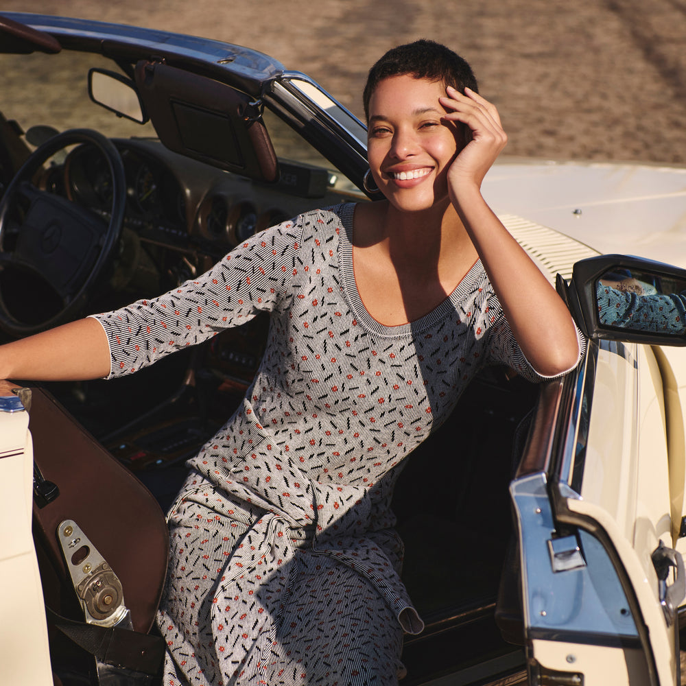 Front image of a woman sitting in a car wearing the Tippy Dress in Brick and Black